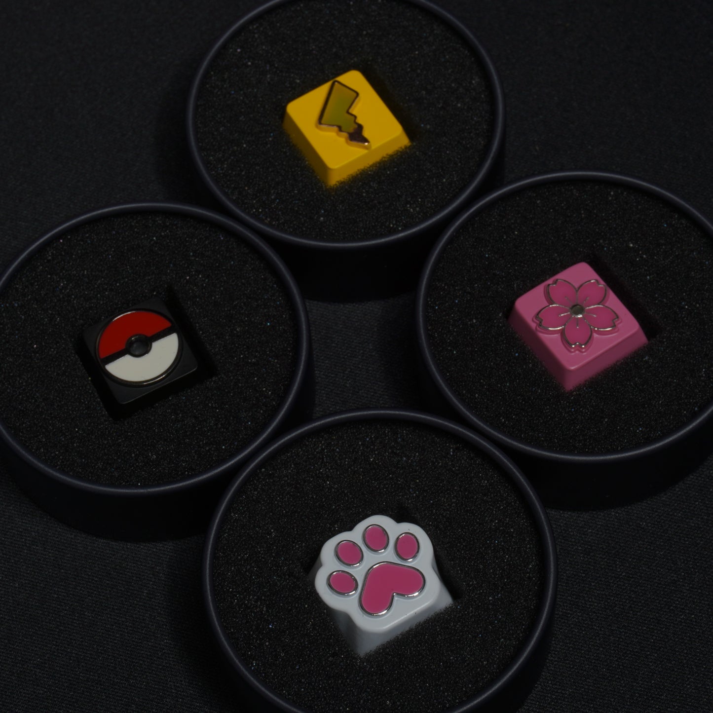 A detail photo of the all of the metal artisan anime keycaps in their packaging tins