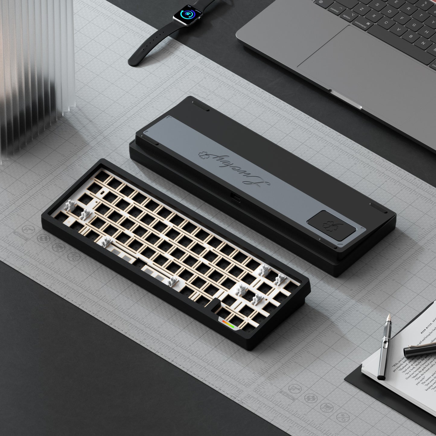Mechanical keyboard components on a desk with laptop, notebook, and pen.