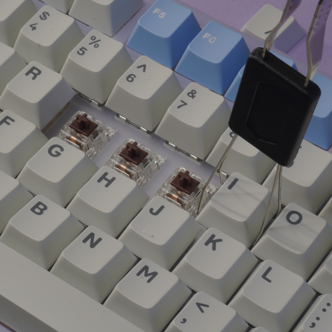Close up photo of the Mathew Tech Mechanical Keyboard and Switch Maintenance Kit Keycap puller, pulling keycaps from a keyboard