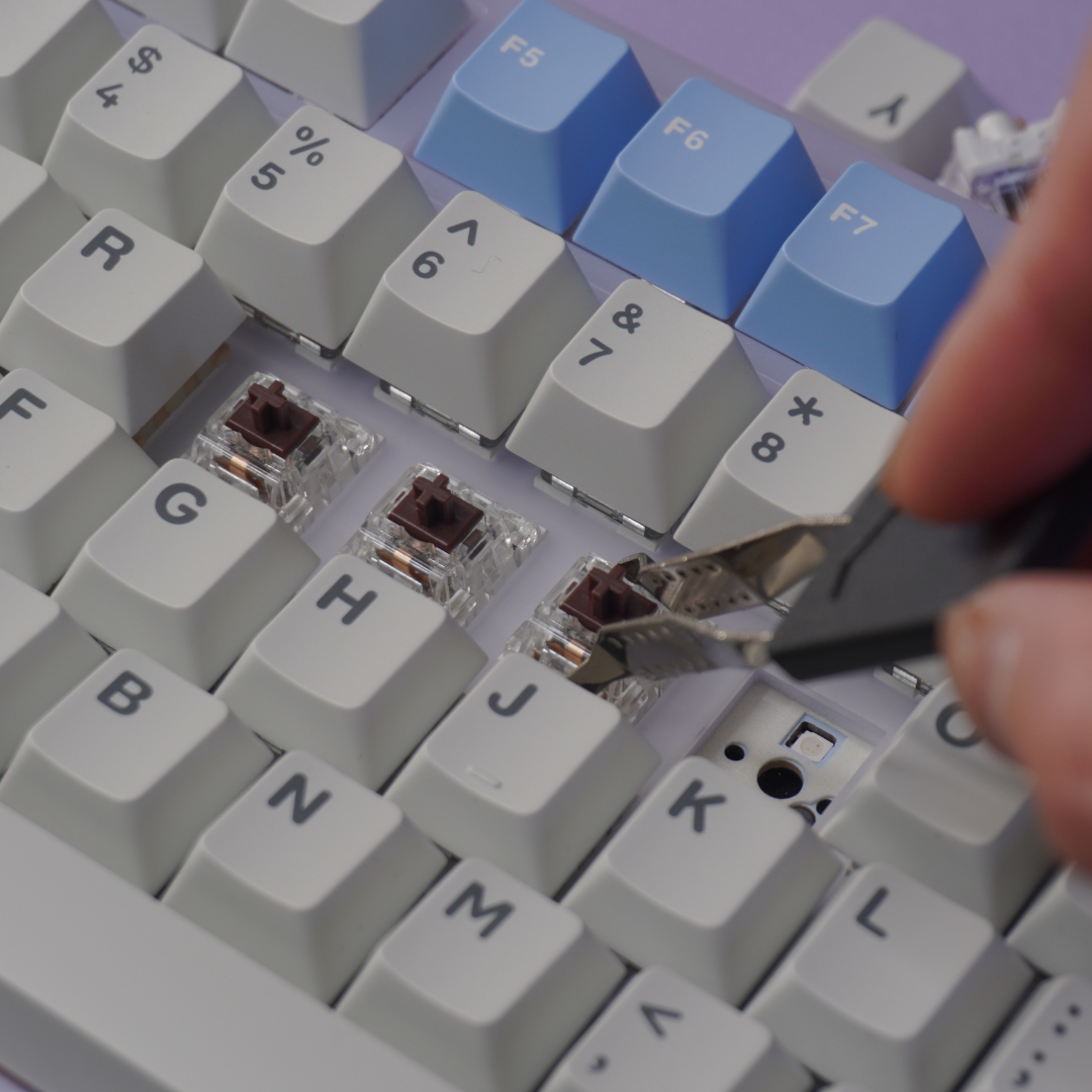 Close up photo of the Mathew Tech Mechanical Keyboard and Switch Maintenance Kit Switch puller, pulling switches from a mechanical keyboard