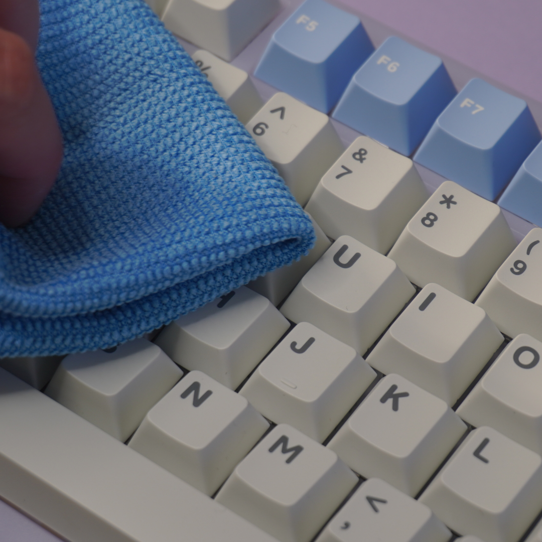Close up photo of the microfiber cloth from the Mathew Tech Mechanical Keyboard and Switch Maintenance Kit wiping away dust and grime from a keyboard