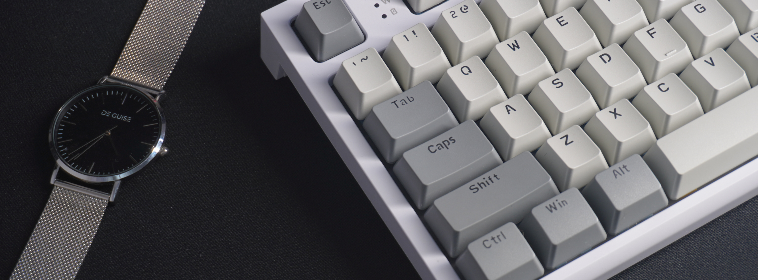 This is a detail Photo of the K86 Attack Shark TKL Business Grey variant mechanical keyboard on a desk with a black desk mat, taken from above on a 45degree angle
