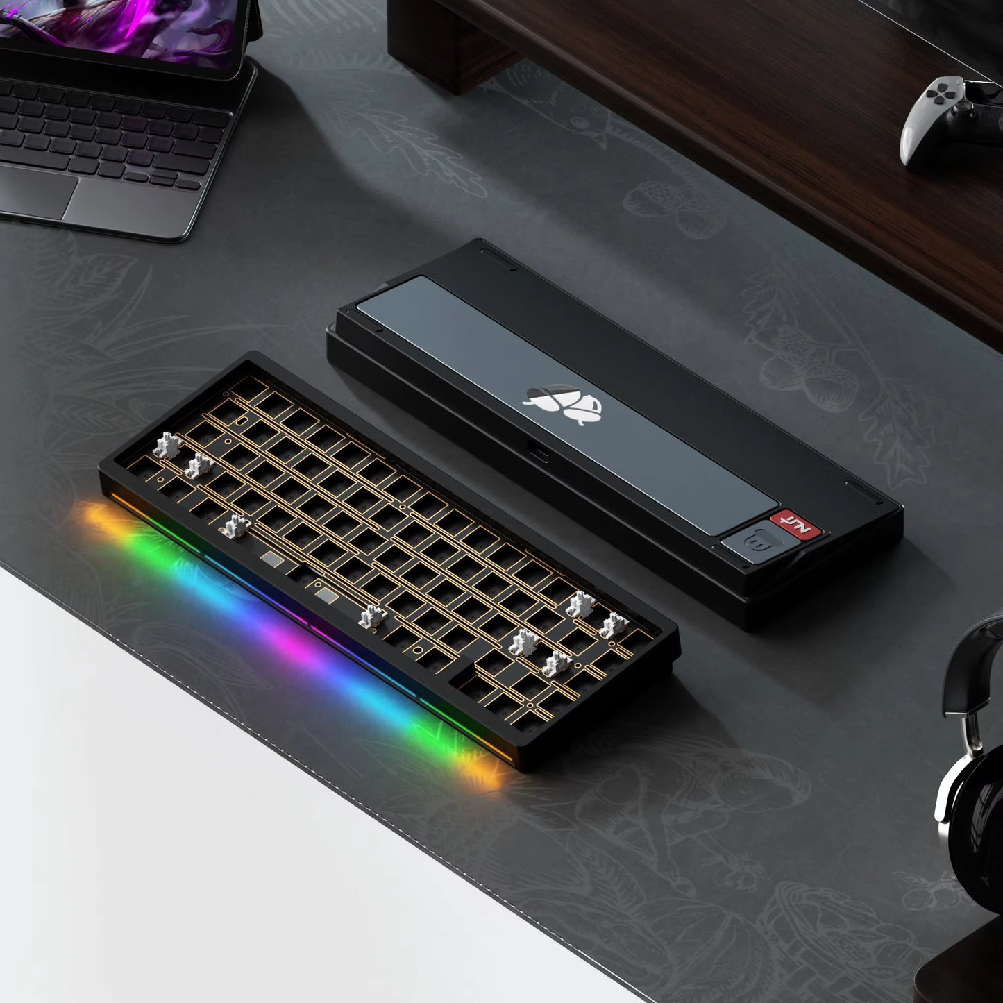 Gaming keyboard with RGB lighting on a desk with a laptop and gaming console.