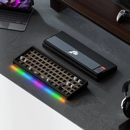 Gaming keyboard with RGB lighting on a desk with a laptop and gaming console.