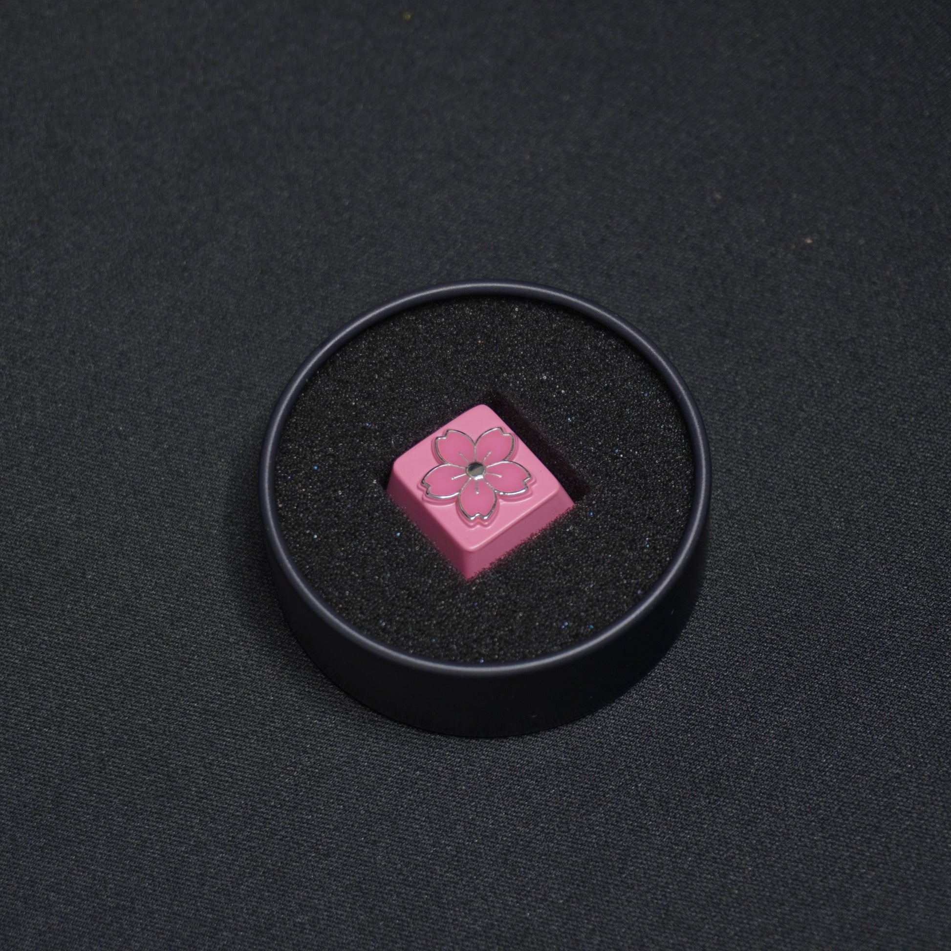 A detail photo of the Sakura metal artisan anime keycap in its Packaging Tin
